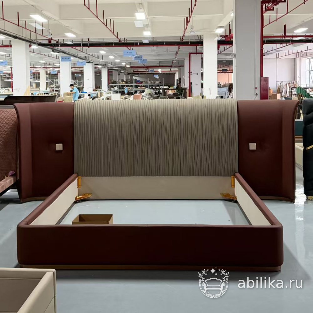 Кровать с широким изголовьем из бордовой кожи и выключателями на боковинах на фабрике